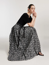 a lady in a rose jacquard pleated horse-faced skirt with black shirt